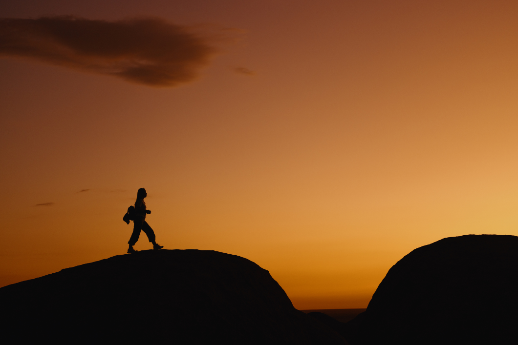 Silhouette of hiker against sunset sky.