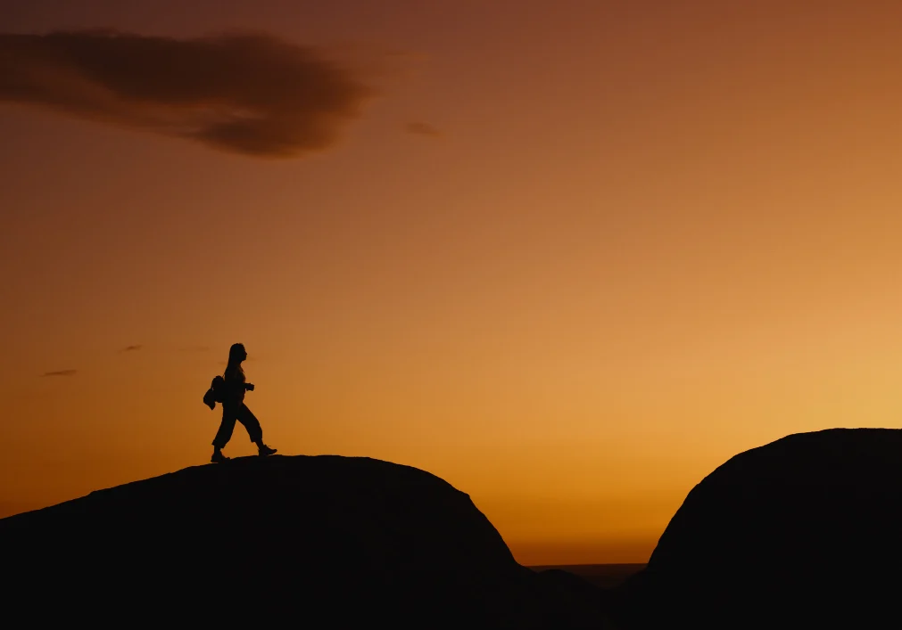Silhouette of hiker against sunset sky.